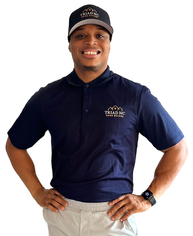 Smiling male real estate professional in a navy blue branded polo shirt with hands on hips.